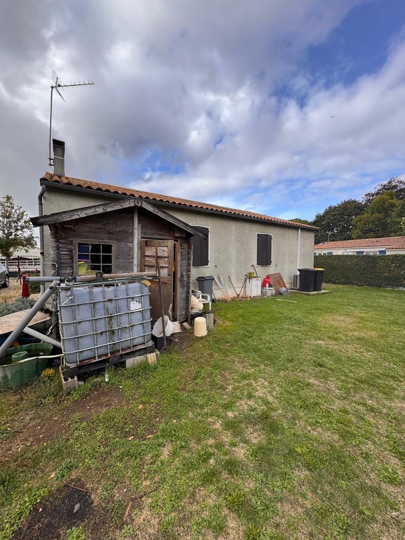 Façade de maison en Charente au crépi beige défraîchi et verdi avant ravalement
